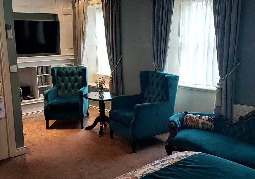 a living room with two blue chairs and a table at Headfort Arms Hotel in Kells