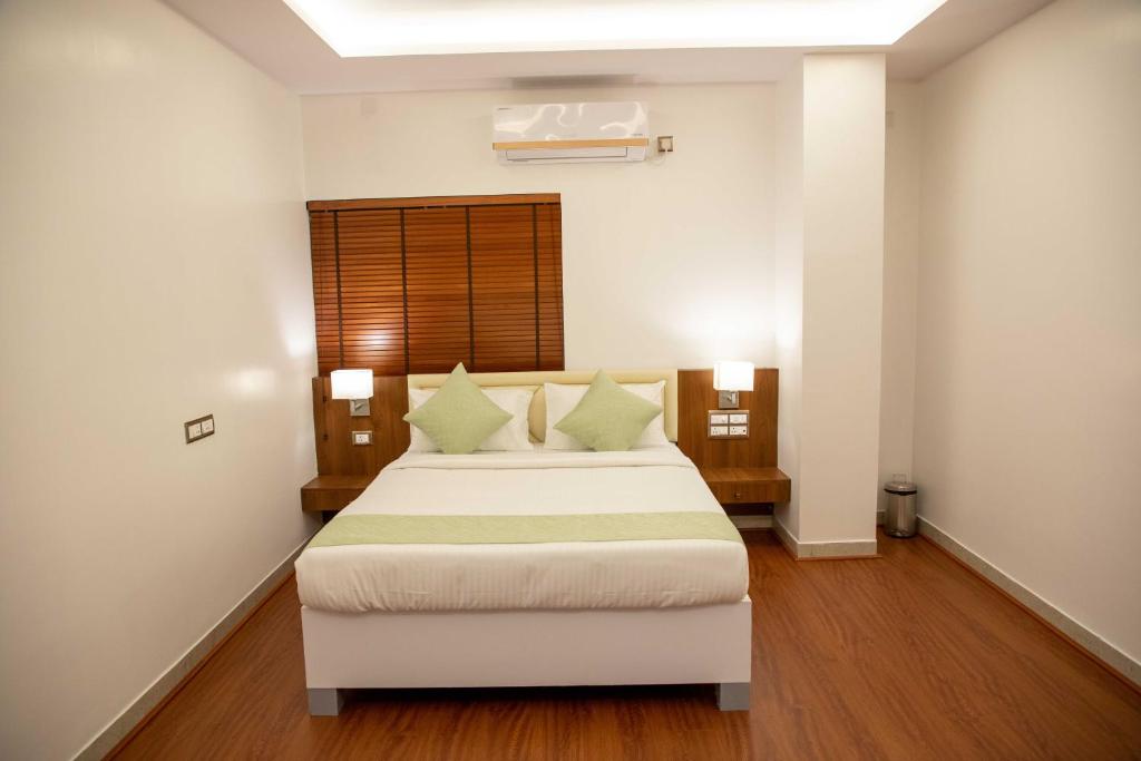 a bedroom with a large white bed with green pillows at PVR Suites off Bannerghatta Road in Bangalore