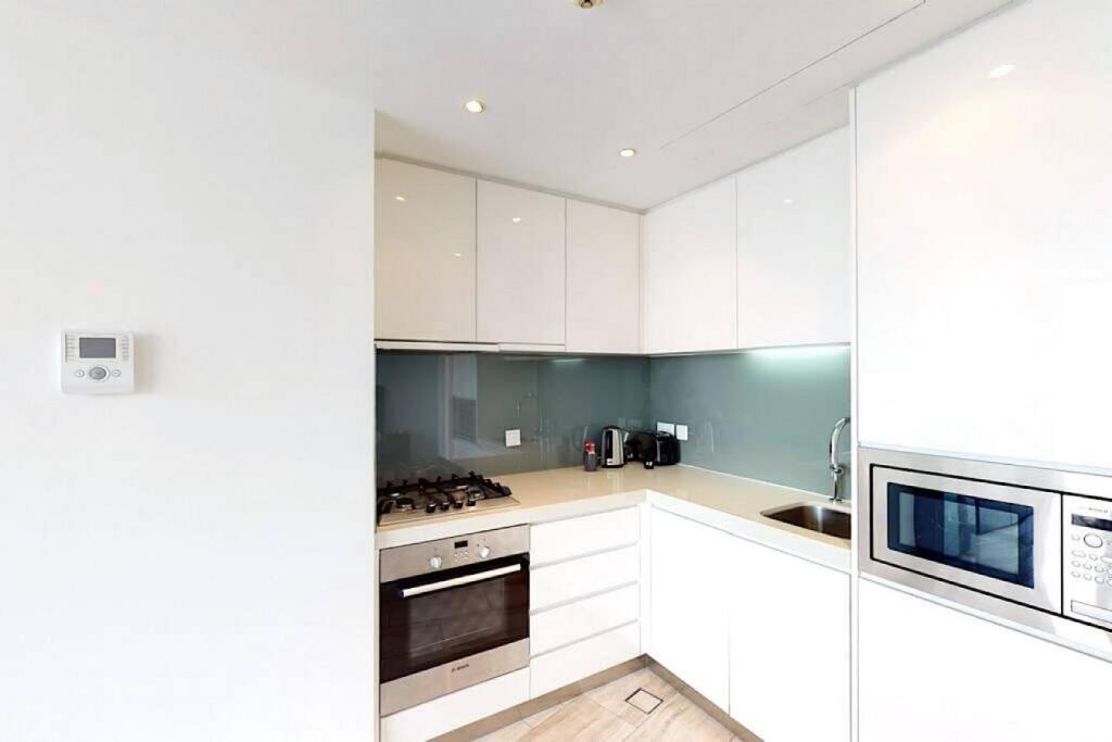 a white kitchen with white cabinets and appliances at Breathtaking Studio - Al Jaddaf in Dubai