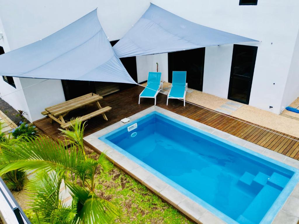 - une piscine avec 2 chaises bleues et un parasol dans l'établissement Villa Aelia - 3 chambres - Piscine privée., à Flic-en-Flac