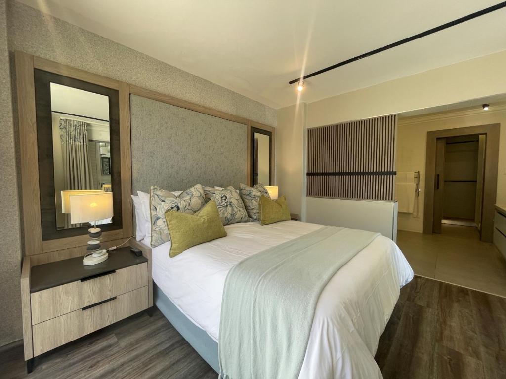 a bedroom with a large white bed and a mirror at Aquarella 2 in Plettenberg Bay