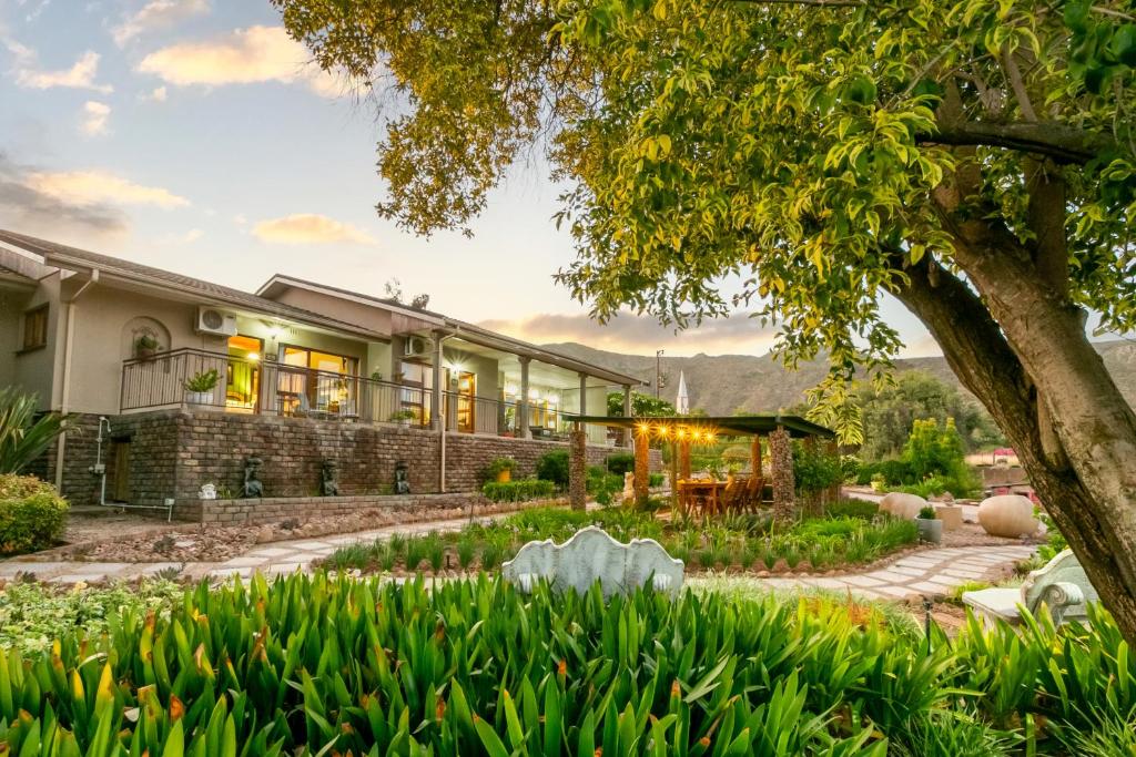 an exterior view of a house with a garden at Die Fonteine Country Guest House in Oudtshoorn