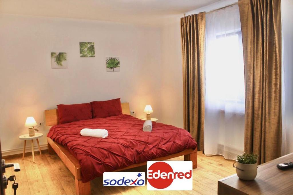 sypialnia z łóżkiem z czerwoną pościelą i oknem w obiekcie Eden Villa w Braszowie