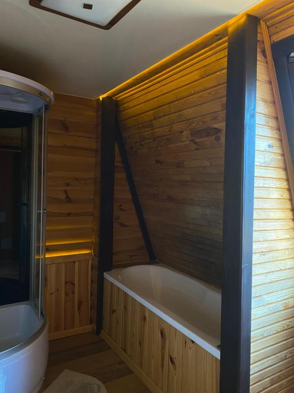 a bathroom with a tub and a wooden wall at California in Khorodelets