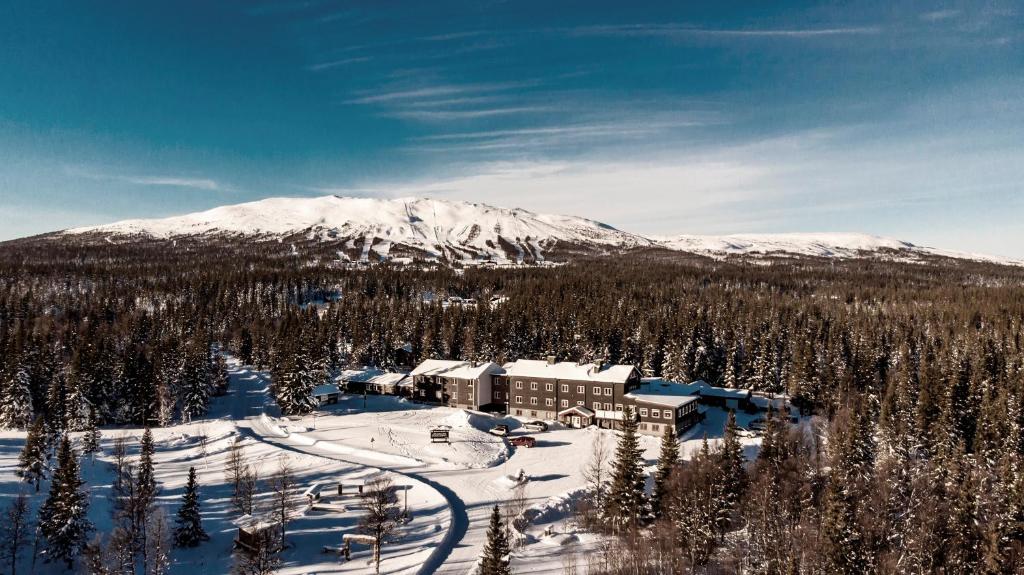 un lodge de esquí con una montaña cubierta de nieve en el fondo en Trillevallens Högfjällshotell & Lägenheter, en Trillevallen