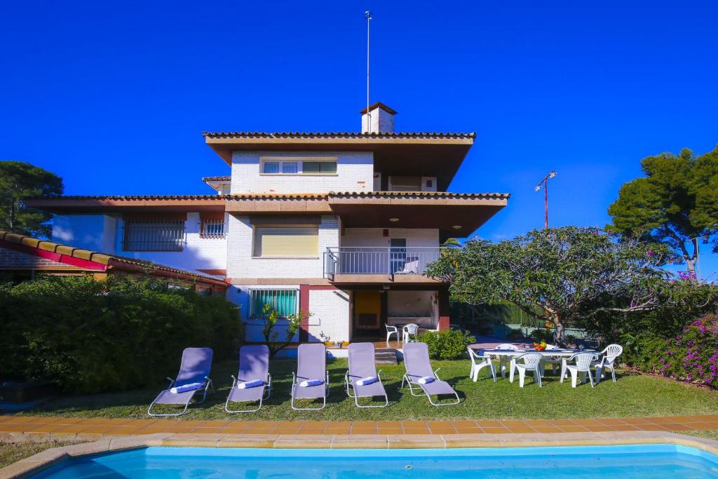 a house with a table and chairs next to a pool at Villa Serena Planet Costa Dorada in Salou