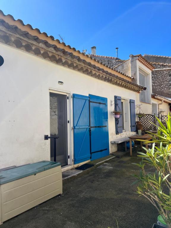 una casa blanca con puertas azules y un banco en Les lauriers rouge, en Peyriac-de-Mer