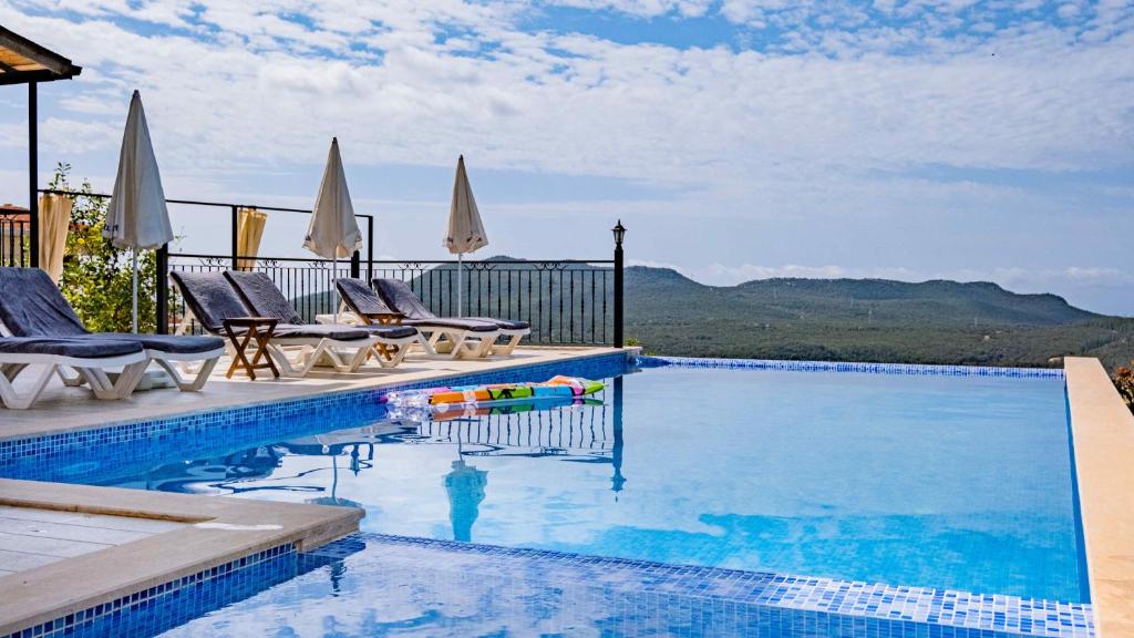ein Swimmingpool mit Liegestühlen und ein Swimmingpool in der Unterkunft VİLLA KAYA in Kaş