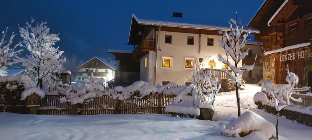 una cerca cubierta de nieve frente a una casa en Lenzerhof en Lappago