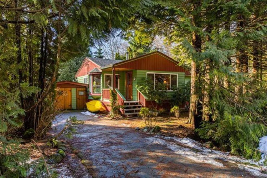 a red and green house in the middle of trees at Vintage Downtown Cabin in Squamish