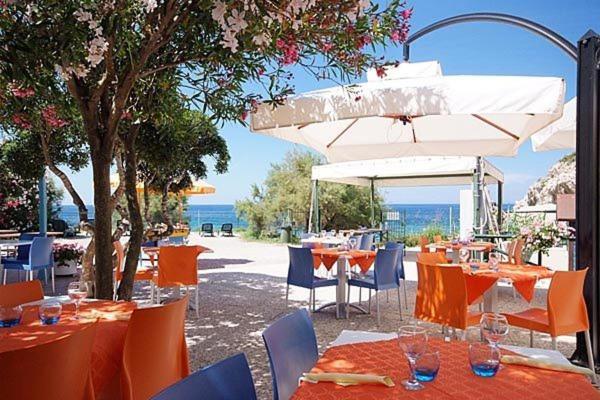 a group of tables and chairs with an umbrella at Acquaviva Village Camping in Portoferraio