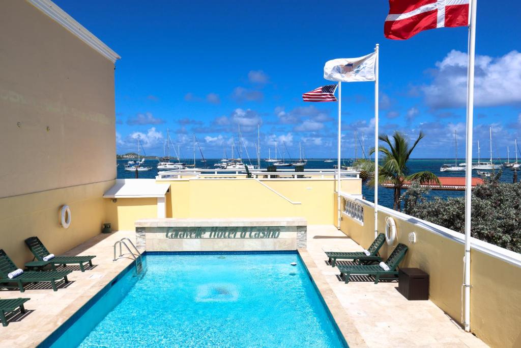 a swimming pool with chairs and flags on a building at Caravelle Hotel in Christiansted