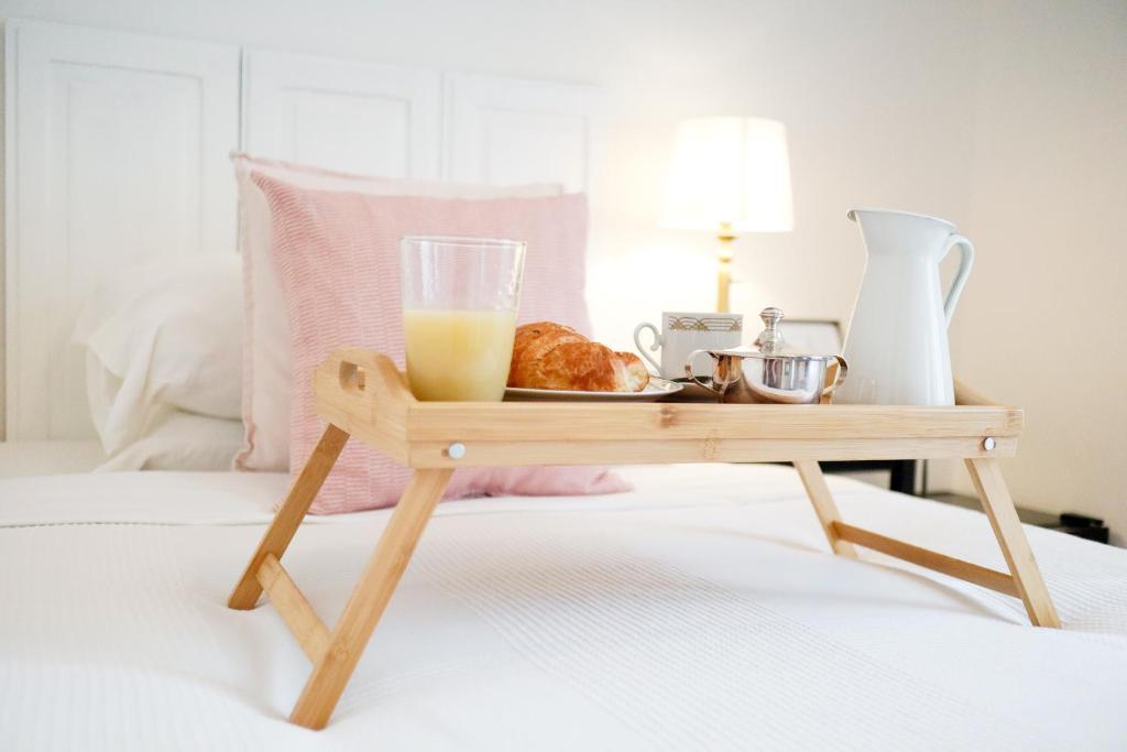 a tray of food and drinks on a wooden table on a bed at Guest House Camilla in Alghero