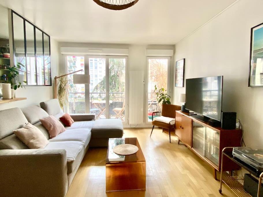 ein Wohnzimmer mit einem Sofa und einem Flachbild-TV in der Unterkunft Grand appartement cosy avec balcon 6 personnes in Saint-Ouen