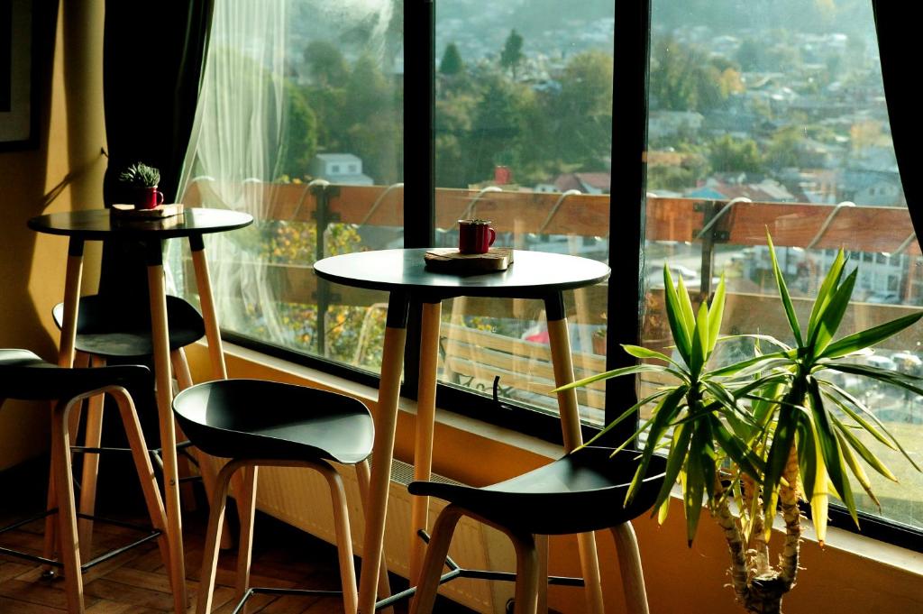 two tables and chairs in front of a large window at Hotel Seminario in Puerto Montt