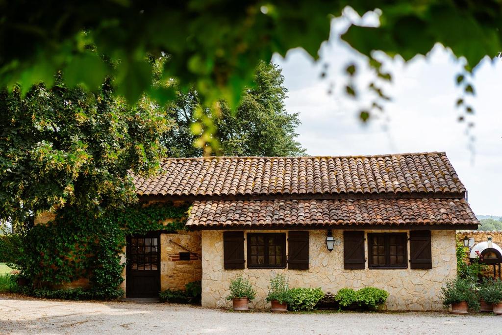 une petite maison en pierre avec un toit dans l'établissement Cosy former bakery house with communal swimming pool, à Prayssac