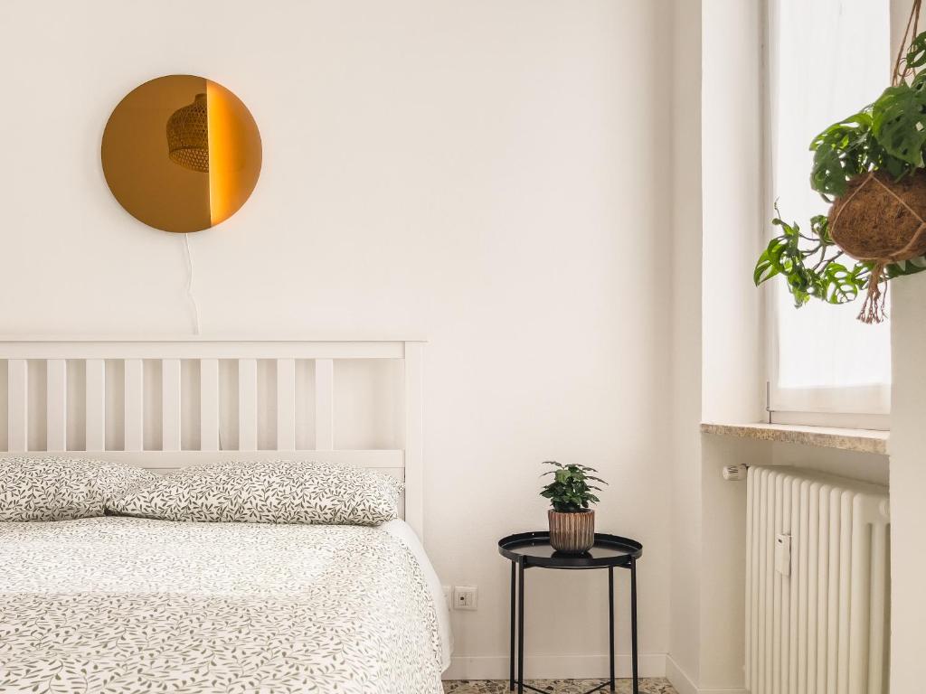 1 dormitorio con cama blanca y espejo redondo en [Freshly renovated] 10 minutes from Arena, en Verona