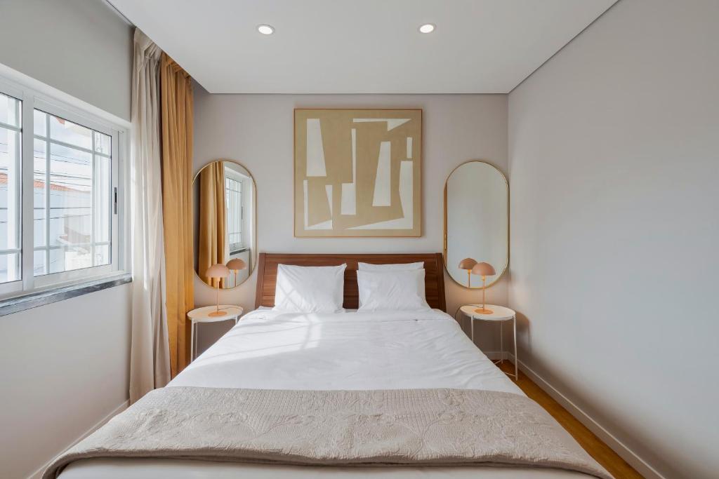 a bedroom with a large white bed and two mirrors at Casa Rosa in Quinta do Conde