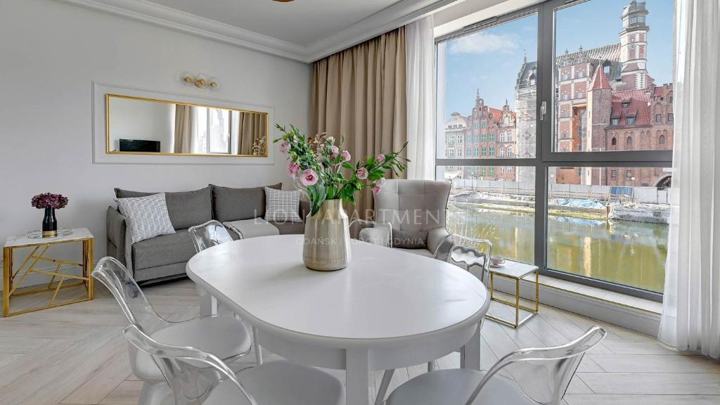 sala de estar con mesa blanca y sillas en Lion Apartments - The Palace premium apartment with Old City & River View en Gdansk