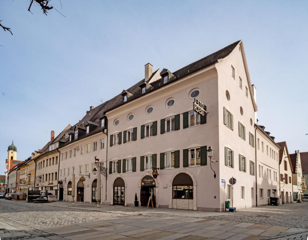 - un grand bâtiment blanc dans une rue de la ville dans l'établissement Hotel Goldener Hirsch, à Kaufbeuren