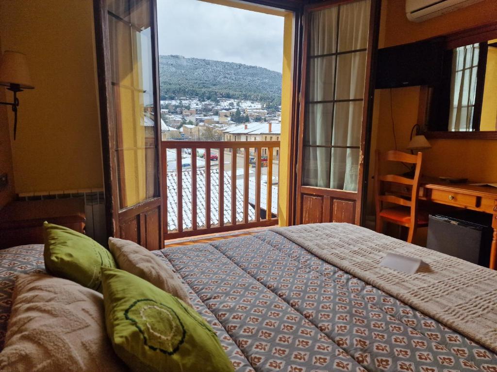 1 dormitorio con 1 cama y balcón con vistas. en Hotel Virginia R.H., en Vinuesa