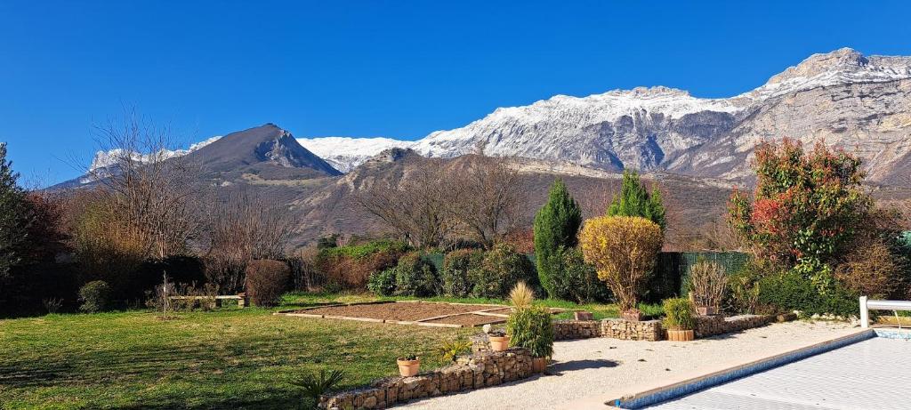 a garden with snow covered mountains in the background at Chambres d'hôtes de Reymure in Vif