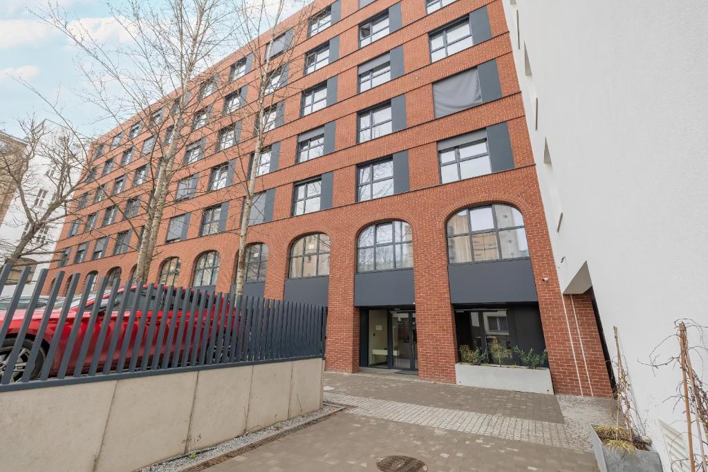 a brick building with a red car parked in front of it at Modern Studios in the Centre of Poznań by Noclegi Renters in Poznań