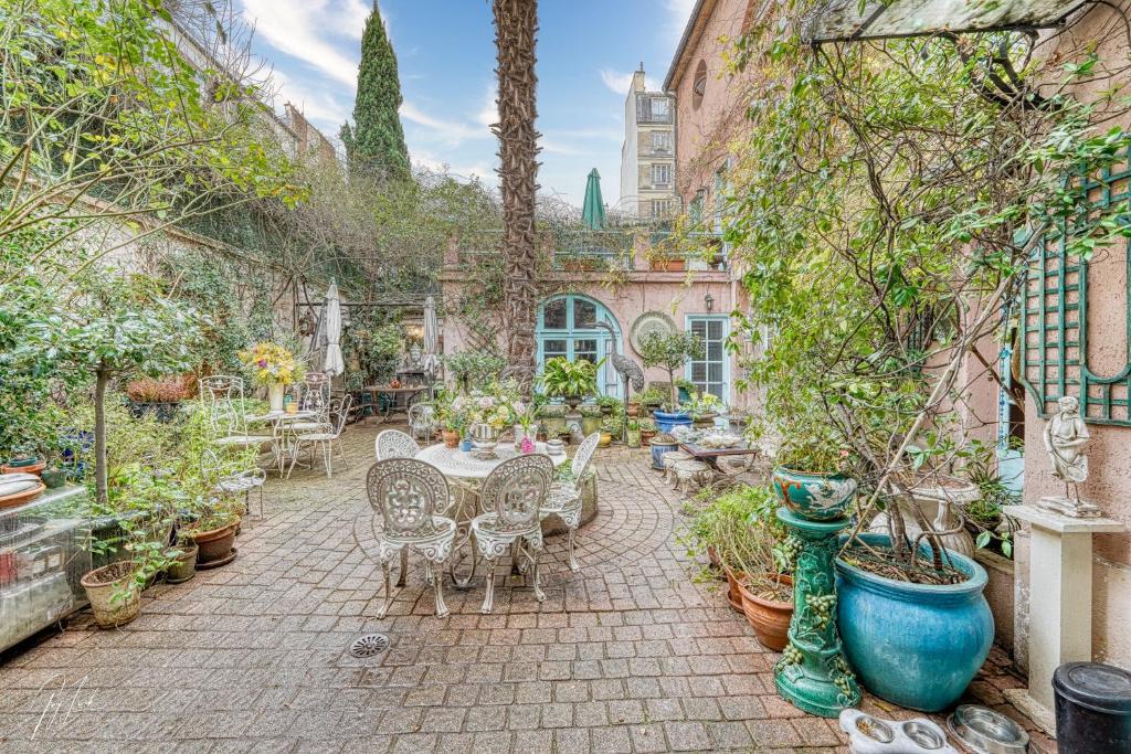 une terrasse avec une table, des chaises et des plantes en pot dans l'établissement "Maison 1850 Paris 18" Chambre avec terrasse et parking en option, à Paris