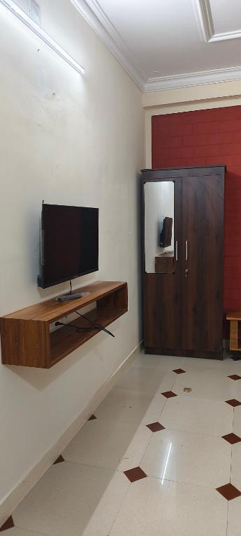 Prakruthi home 2 في منغالور: غرفة معيشة مع تلفزيون بشاشة مسطحة على جدار