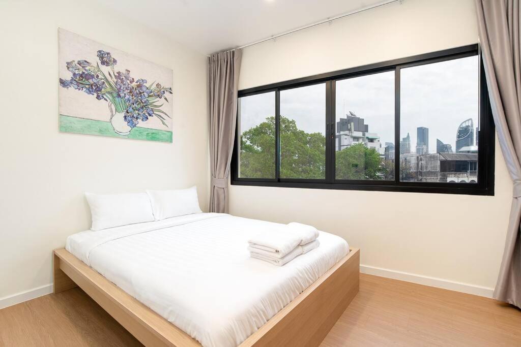 a white bedroom with a bed and a window at Townhouse in Pratunam Bangkok in Bangkok