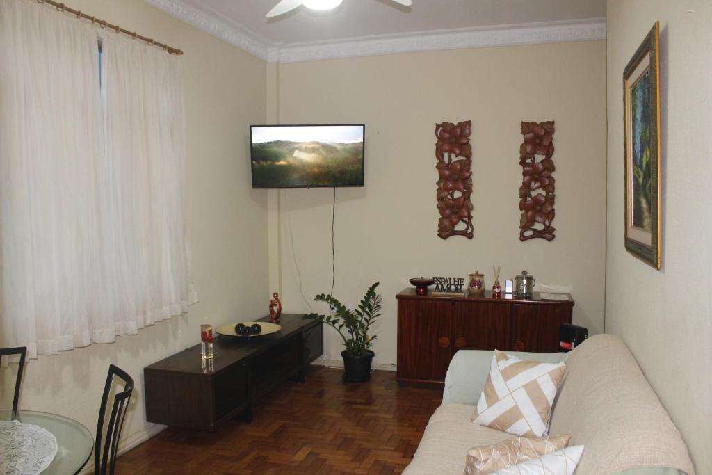 ein Wohnzimmer mit einem Sofa und einem TV an der Wand in der Unterkunft Anfitrioca Apartamento Gloria in Rio de Janeiro