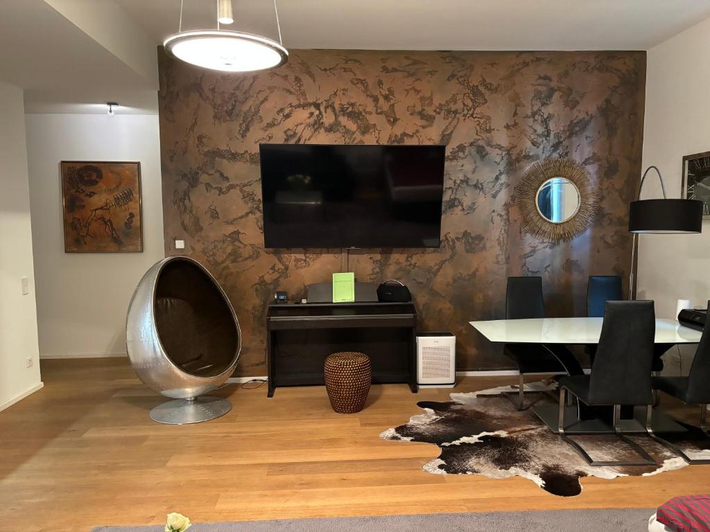 een woonkamer met een tafel en een tv aan de muur bij Luxusapartment Hamburg Hafencity in Hamburg