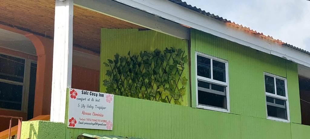 a green building with a window with a sign on it at Salz Cozy Inn in Roseau