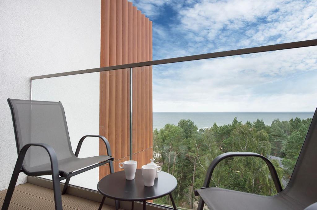 a balcony with a table and chairs and a view of the ocean at Apartament Premium Sea View PINEA 712 in Pobierowo