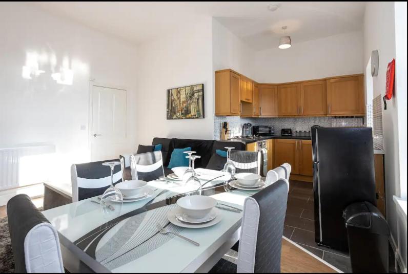 a dining room with a table and chairs and a kitchen at 2 Bed Flat Prenton - Apartment 3 in Birkenhead