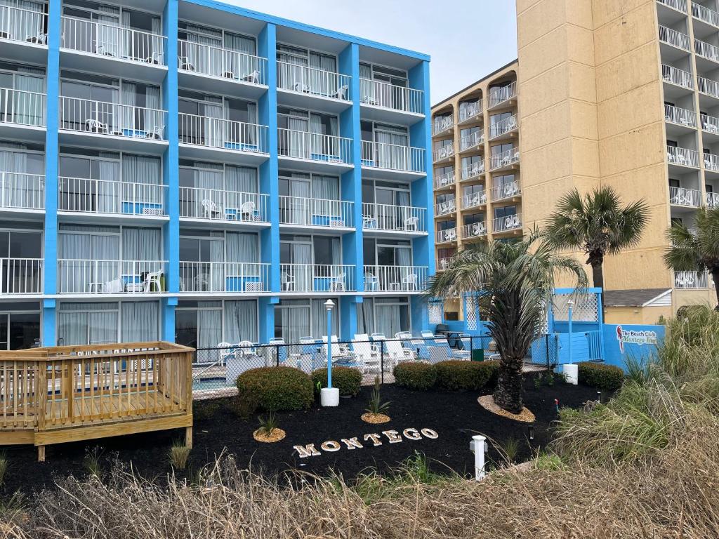 a large apartment building with palm trees in front of it at Beach Club at Montego Inn in Myrtle Beach
