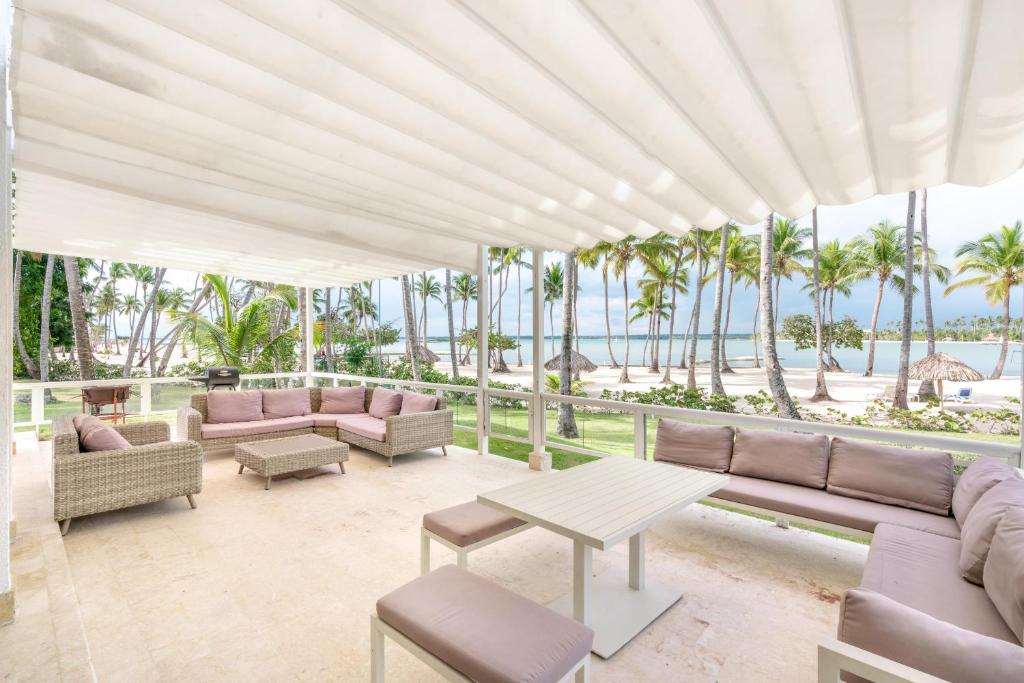 een patio met banken, een tafel en palmbomen bij Beach front and beach access at Nueva Romana in Juan Dolio