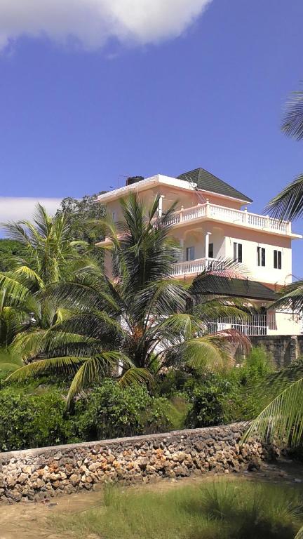 a large white house with palm trees in front of it at Bamboo House BnB in Bondeni