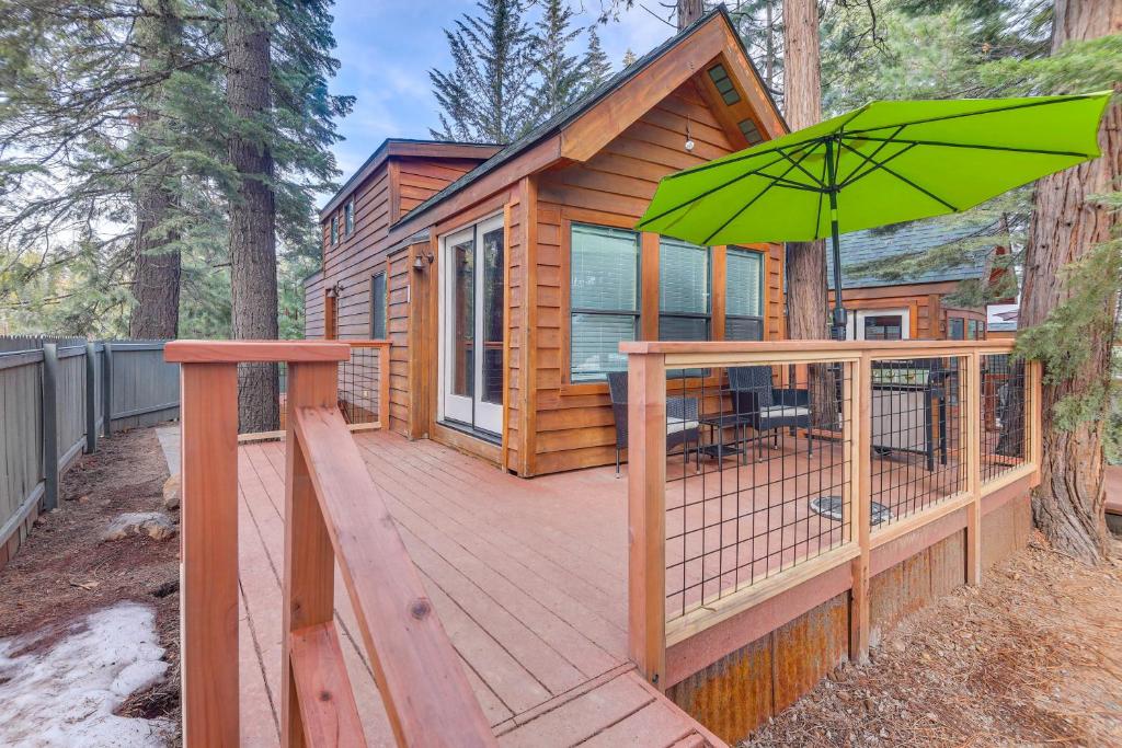 a cabin with a deck with a green umbrella at Quiet Lake Almanor Cabin, Steps to Fishing in Lake Almanor