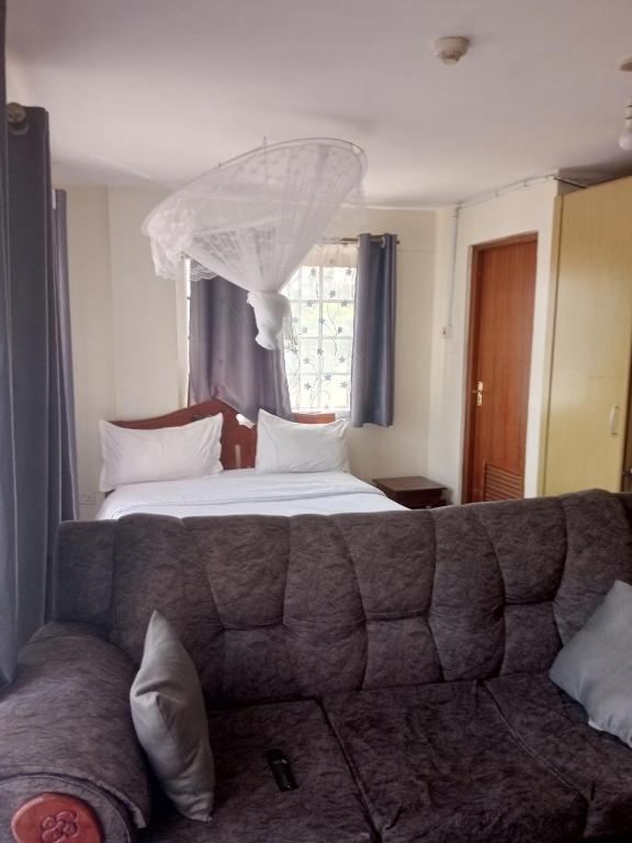 a bedroom with a bed and a couch in front of a window at Best suites Mvuli in Nairobi
