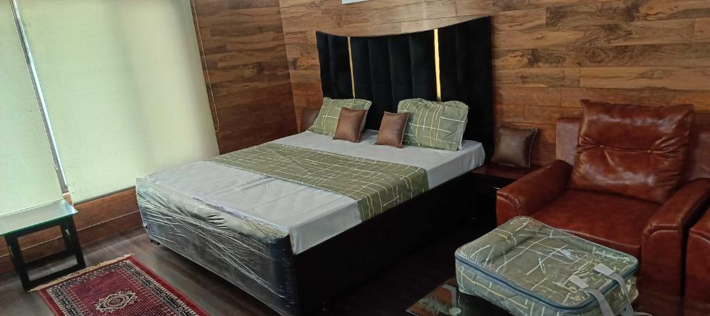 a bedroom with a bed and a chair at Homewood Suites And Guest House in Jammu