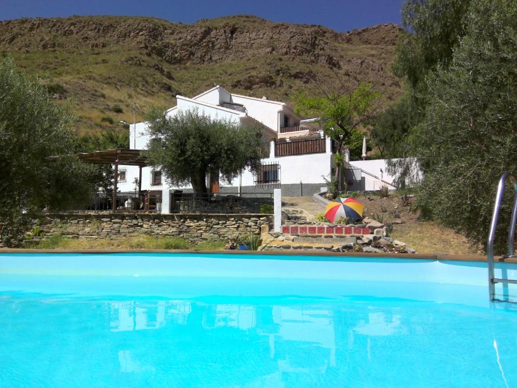 a house and a swimming pool in front of a house at Casa 44, Delightful rural cottage with pool. in Lubrín
