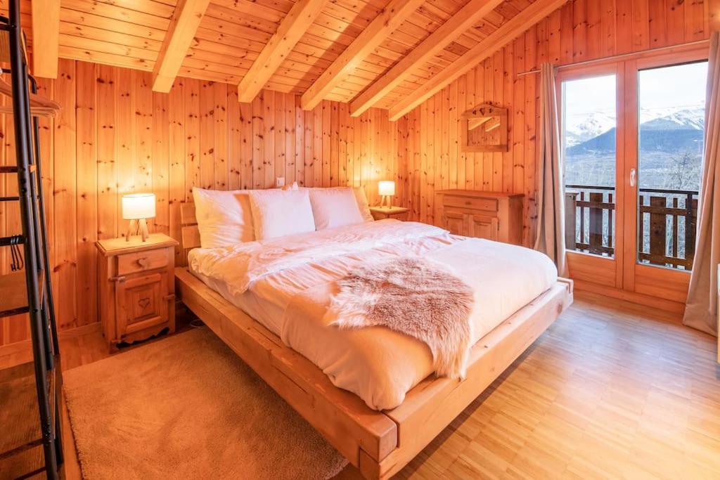 Grand Chalet Veysonnaz w/Spa في سيون: غرفة نوم بسرير في غرفة بجدران خشبية