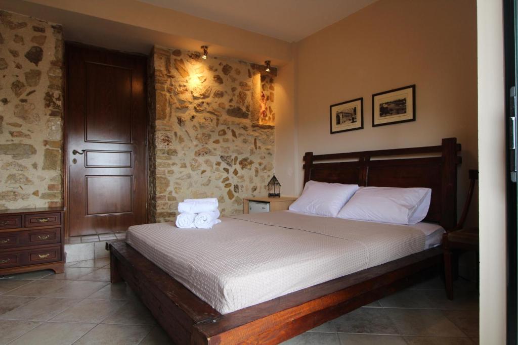 a bedroom with a large bed with white sheets at Corfu Ariandi Stone House in Giannádes