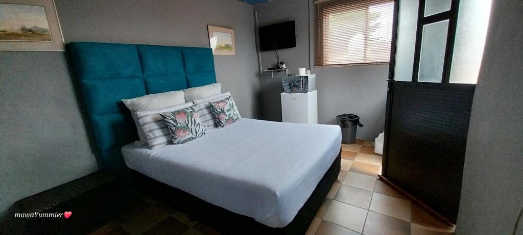 1 dormitorio con cama blanca y cabecero azul en Rato Thato Guest House en Durban