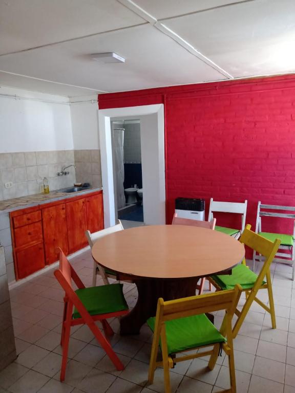 a table and chairs in a kitchen with a red wall at Depto amoblado 3 habitaciones calle 3 de Caballería 463 in Gualeguaychú
