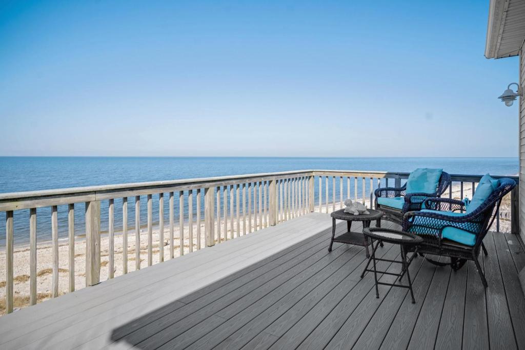 a deck with two chairs and a table on the beach at Queen Vic Beach House: 5 min to Vineyards & Farmstands in Wading River