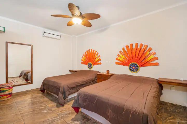 a bedroom with two beds and a ceiling fan at Tai Condo 3 in Barra de Navidad