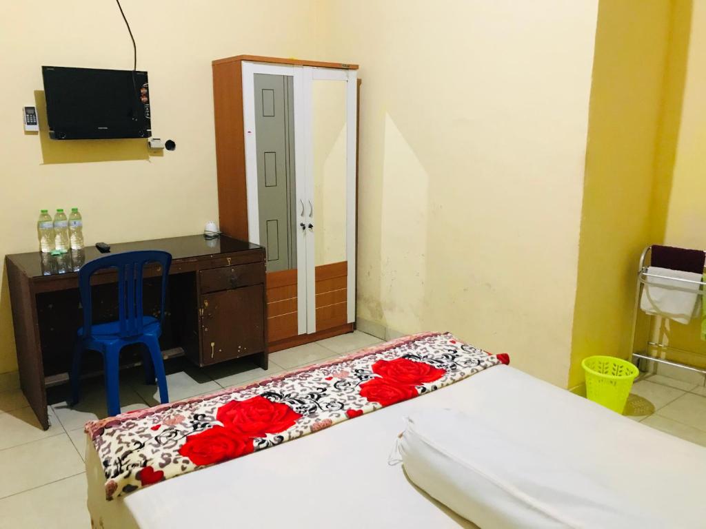 een slaapkamer met een bed, een bureau en een spiegel bij Wisma Dhana Syariah in Praya