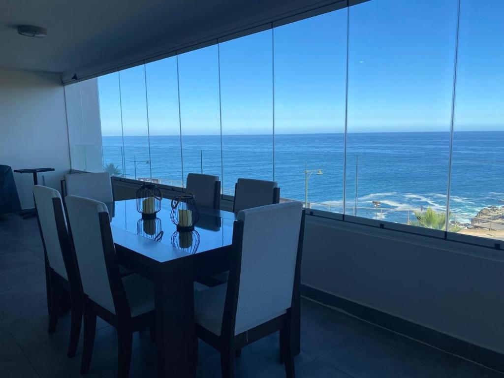 a dining room with a table and chairs and the ocean at Departamentos Mednav Montemar & Spa in Concón